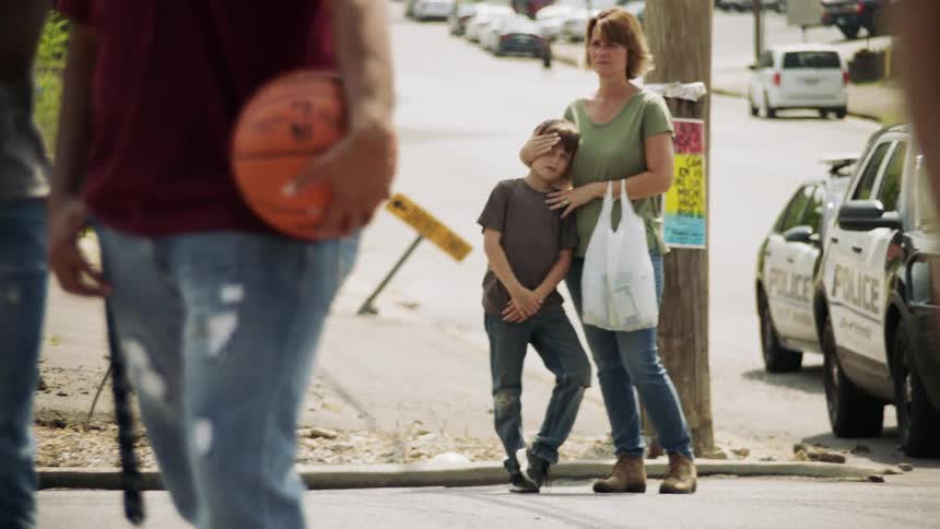 A woman hugs her son on the sidewalk