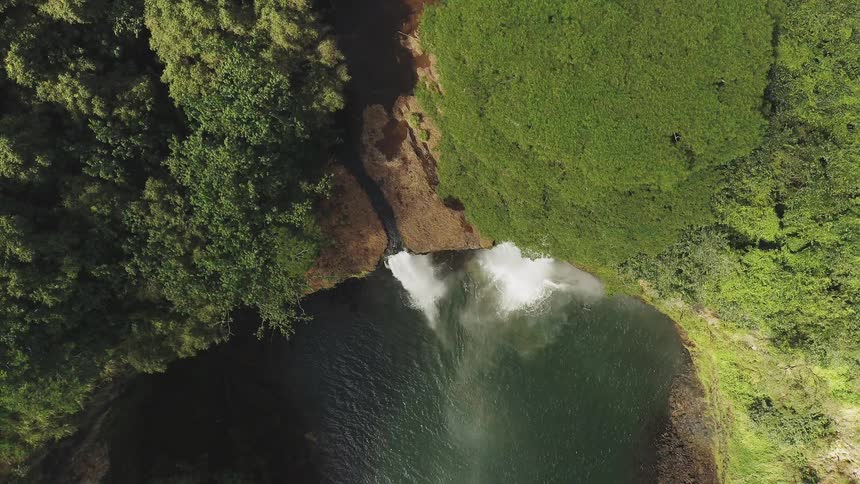 The waterfall has a green cliff above