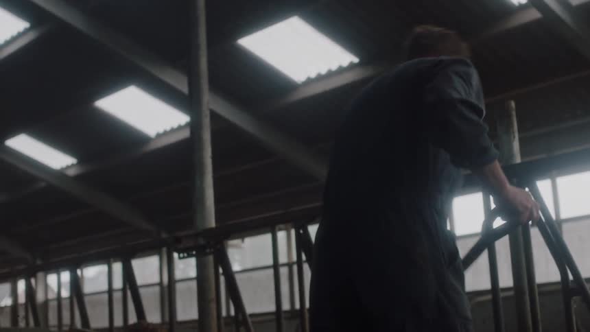 A farmer pitching hay in a barn