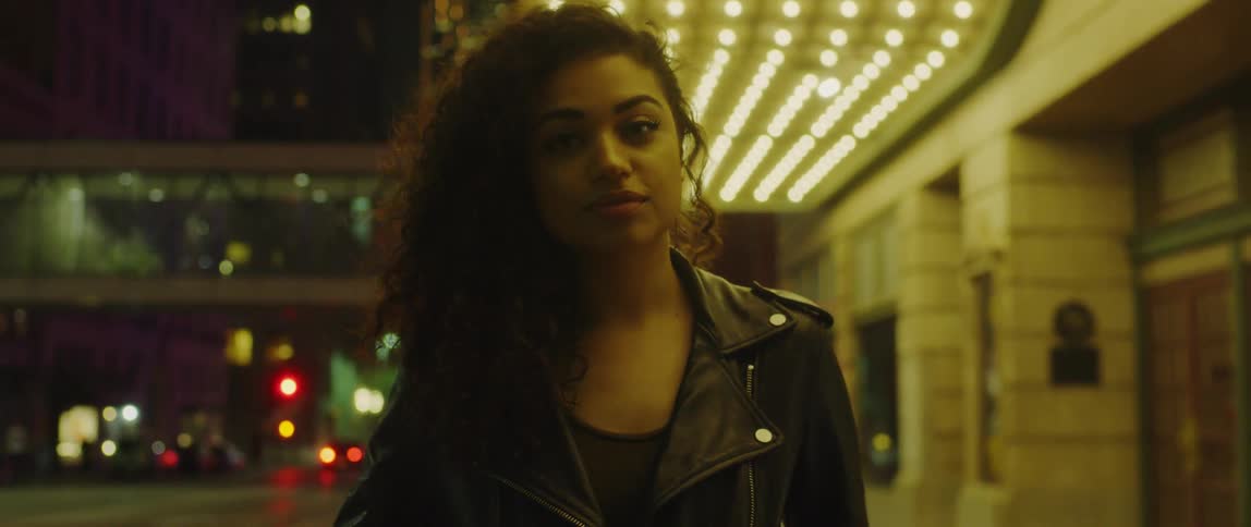 A woman looks around the building at night