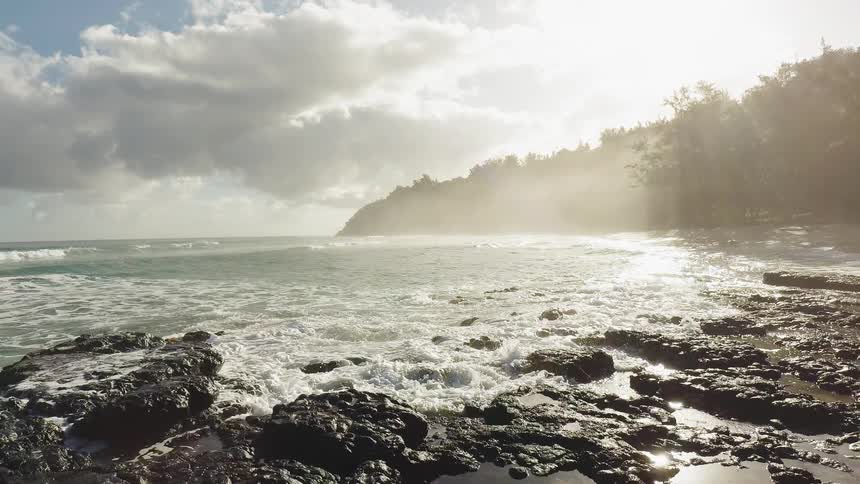 The waves crash against the shore at sunrise