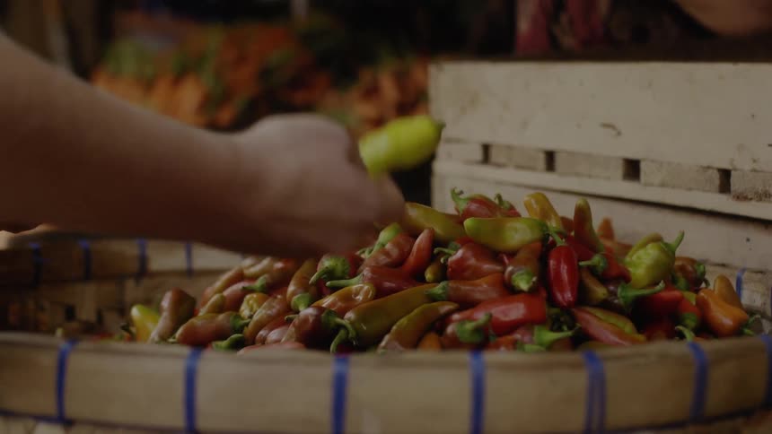 A person picks up and selects chilies in a market