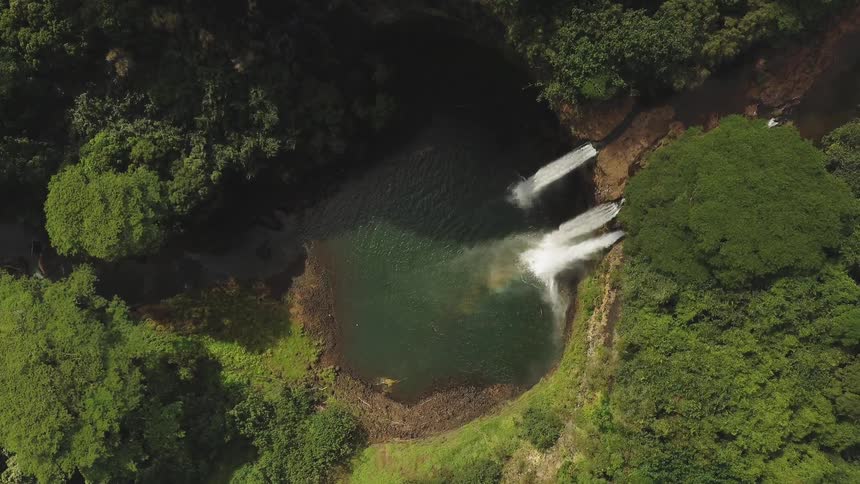 A waterfall flows into a tree lined basin