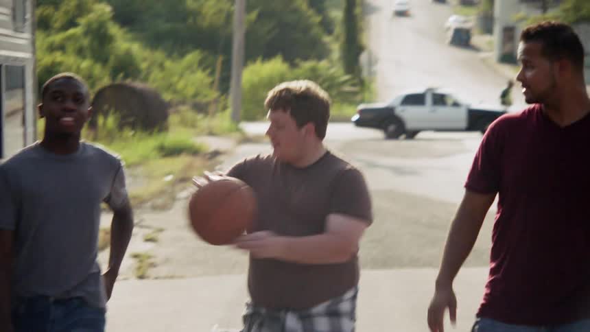 Three people are walking down the street playing with a basketball