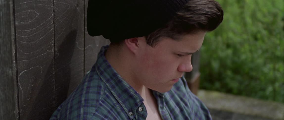 A teenager spins a skateboard wheel while thinking