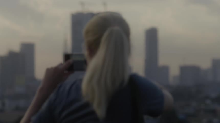A woman uses her phone to photograph the city skyline