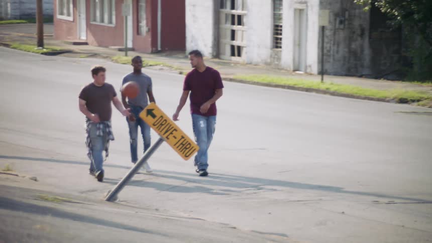 A group of men walk down the street while passing a basketball
