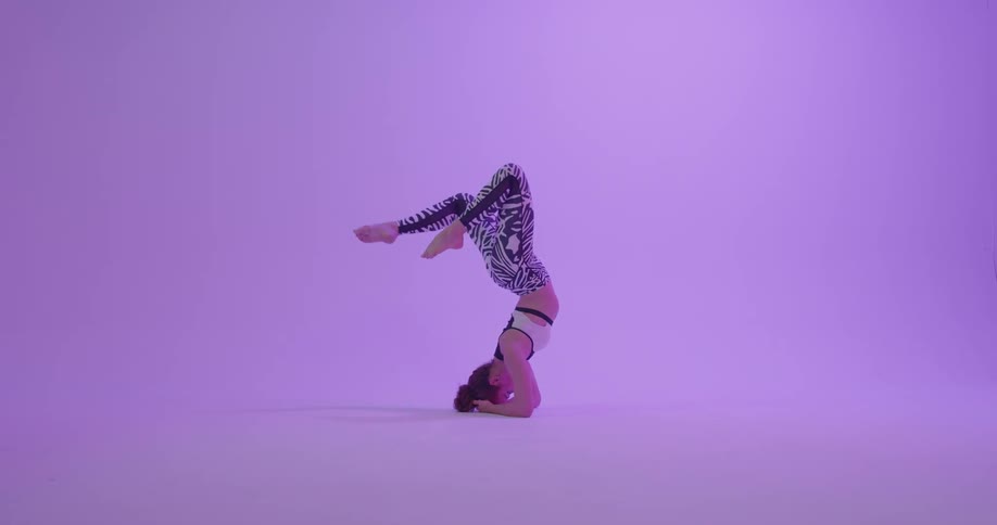 A woman stretches her legs over her body while her head is on the floor
