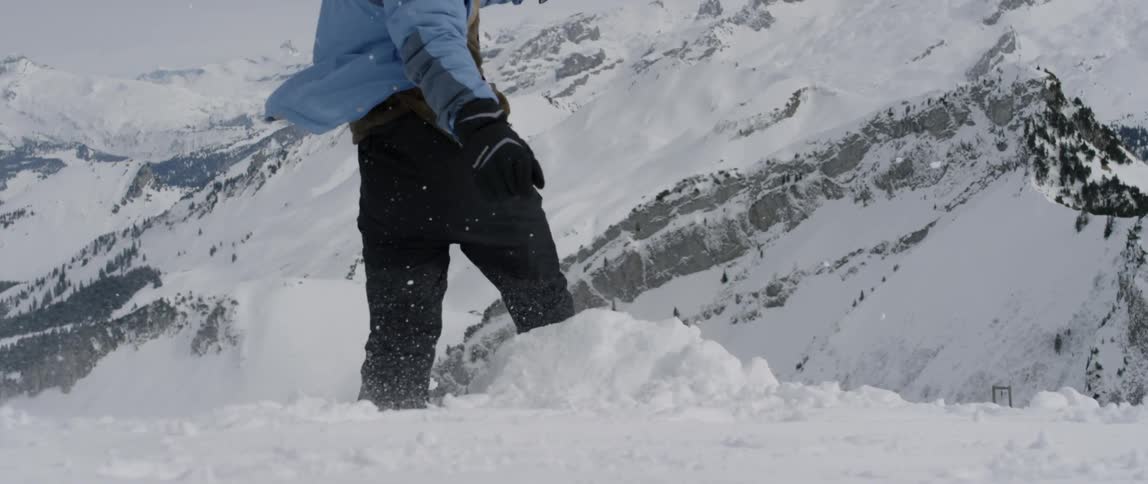 A man runs up and kicks a pile of snow