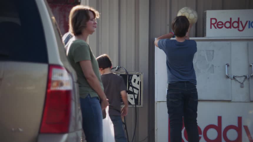A boy plays with a soccer ball outside a gas station