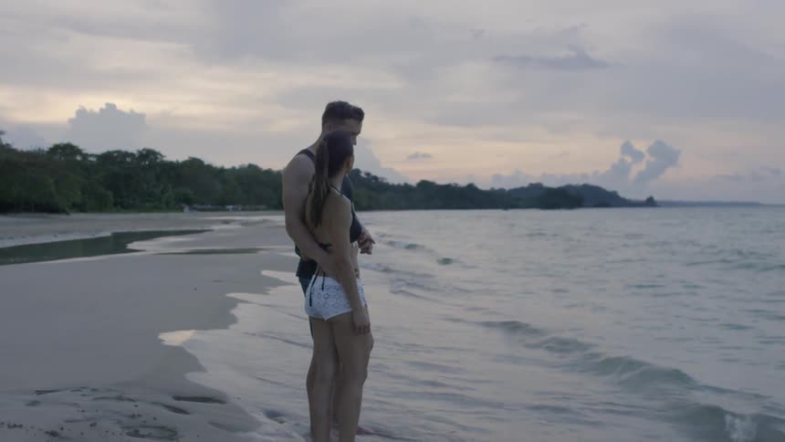 A man has her arm around a woman on the beach