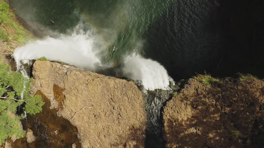 Water falls off the side of a stone cliff