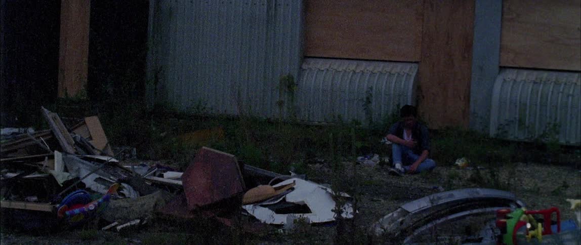 Man sits in front of a building near a pile of debris