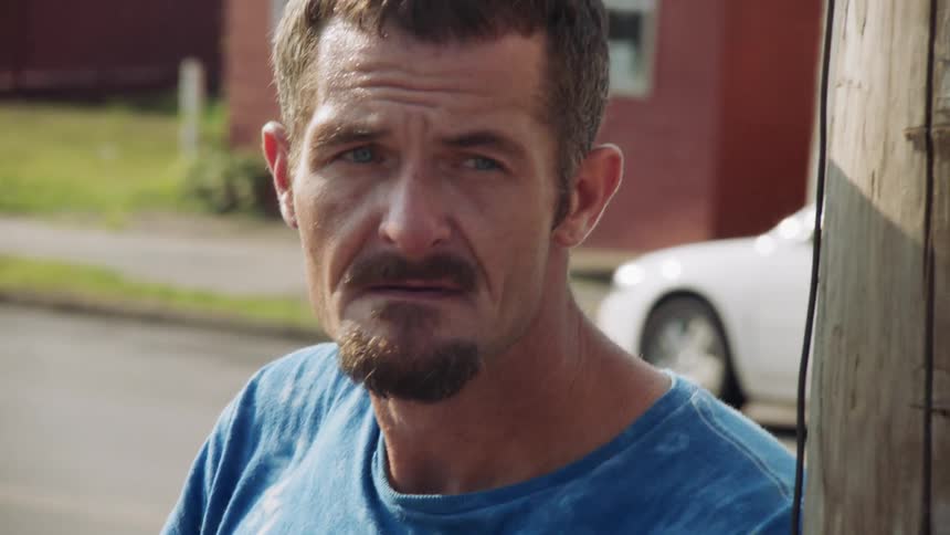 A man smokes a cigarette on the street