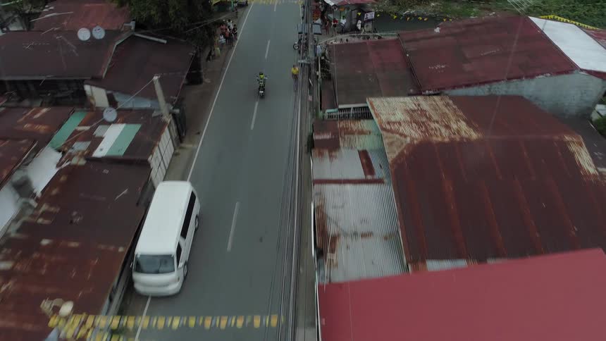 Motorcyclists and cars drive through a town