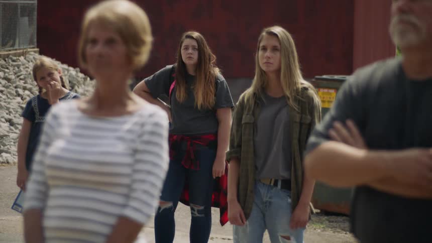 A group of people are standing outside looking at something off camera