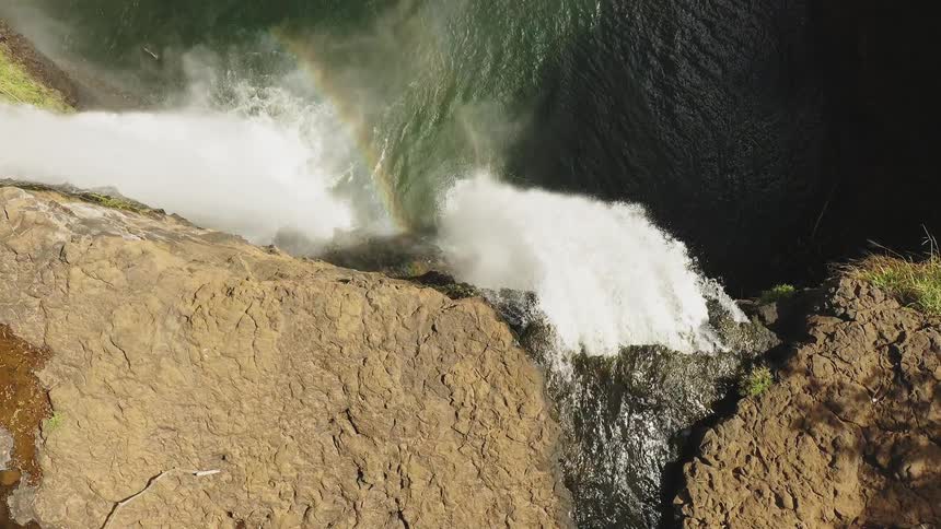 Water flows over a cliff and into the ocean