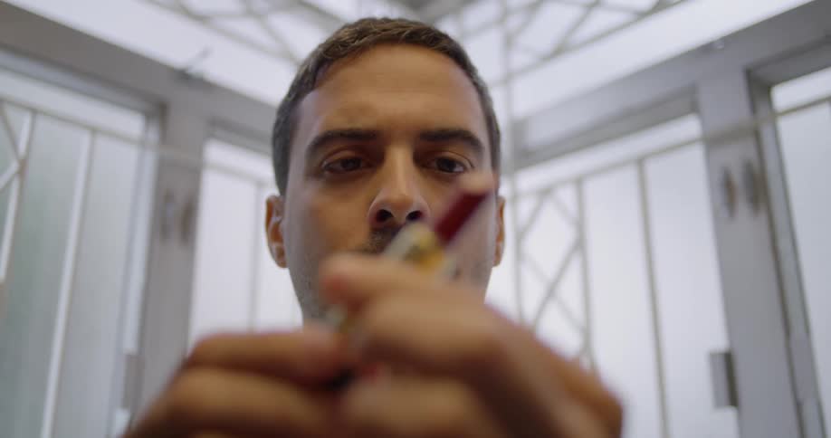 A man looks at a tube of lipstick