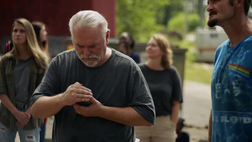 A man shades his phone with his hand while he looks at it