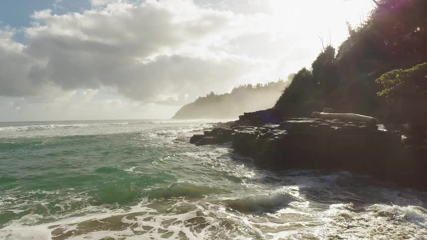 The large waves crash against the rocks by the shore