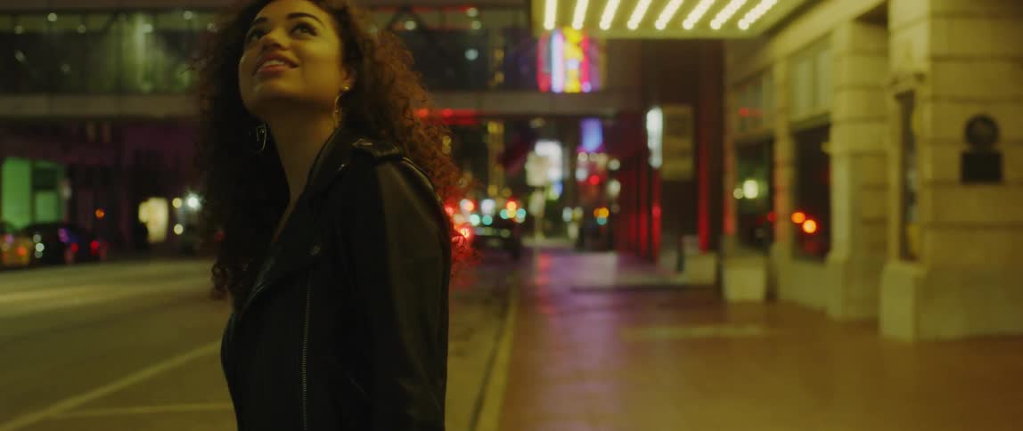 A woman stands on a city street at night