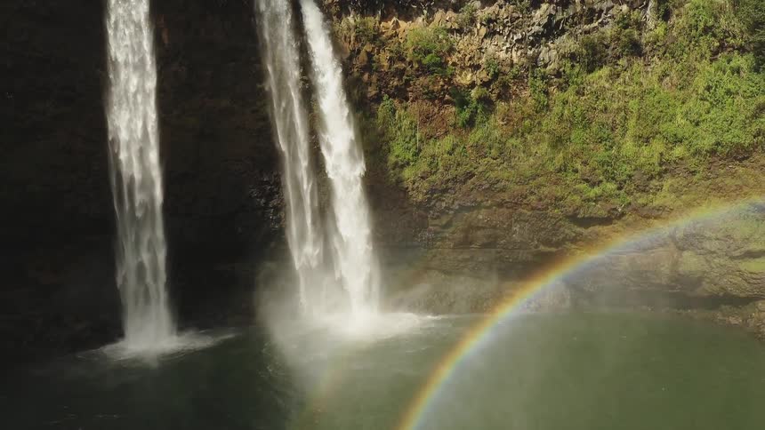 A rainbow shines near waterfalls