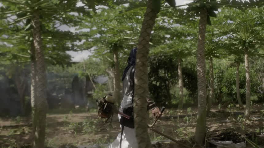 A woman is carrying a gas trimmer in the forest