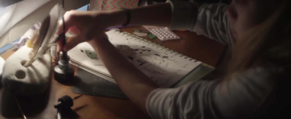 A blonde girl dripping ink onto her hands and arm