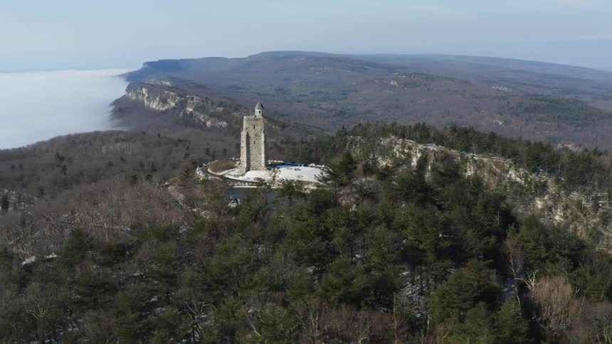 A tall stone building sits on the hill by the shore