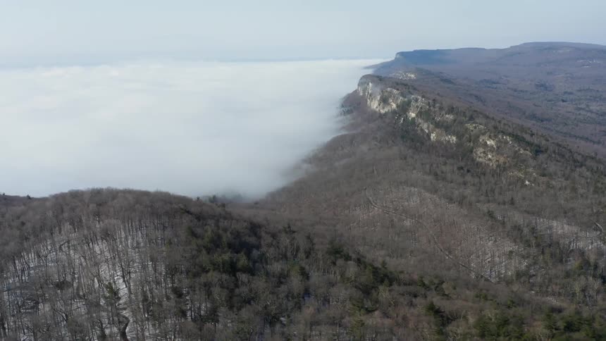 A layer of fog leads up to hills and ridges
