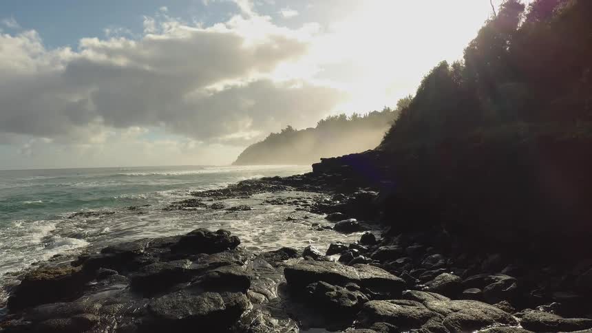 Ocean waves splash against the rocky shore on a sunny day