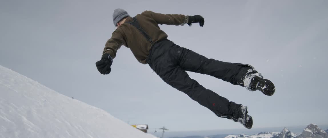 The man jumps and lands in the snow bank
