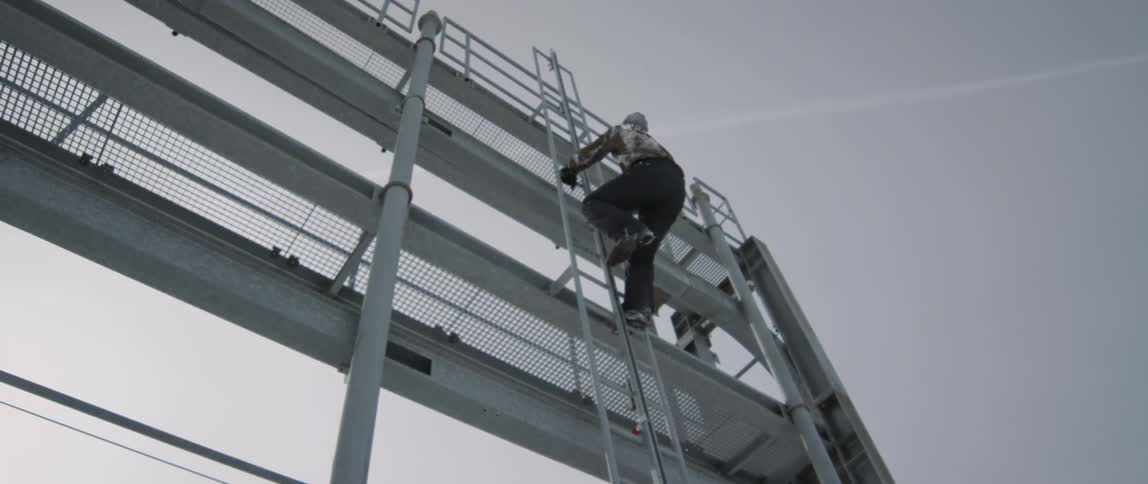 A man is climbing up the metal ladder