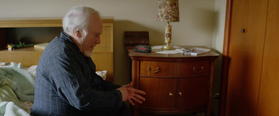 A man sits up then walks out of the room