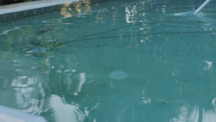 Man stands at the edge of the pool and vacuums it