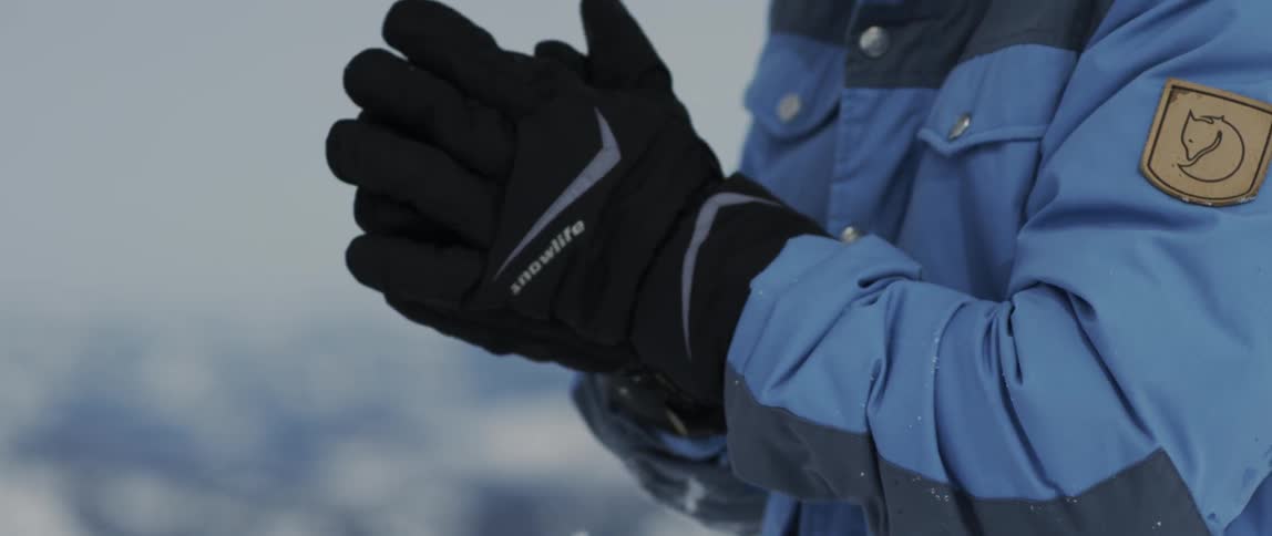 A person rubs their hands together wearing large gloves