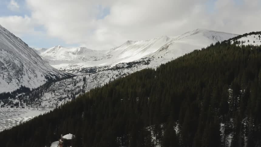 The trees cover the hills of this snow covered mountain range