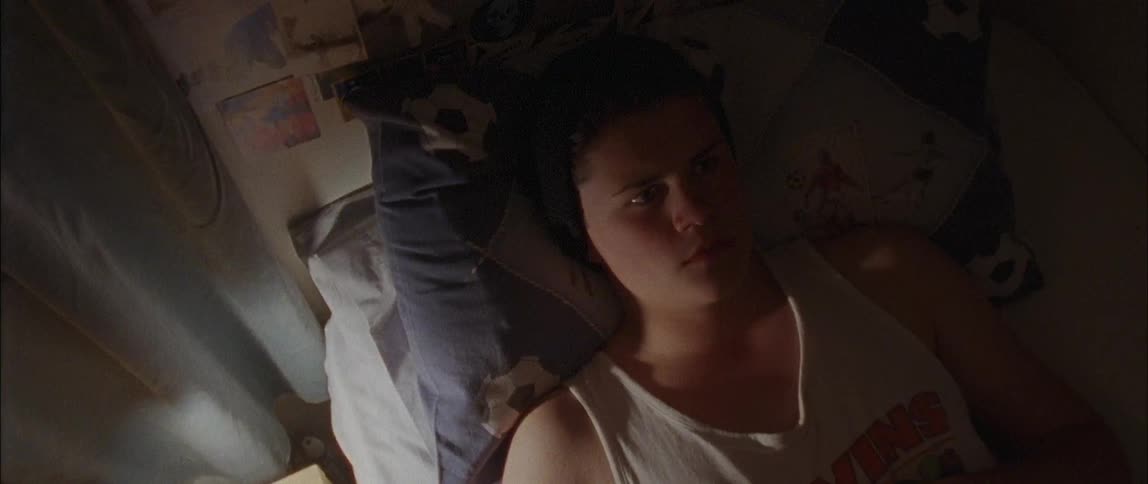 A young boy lays in his bed and sits up