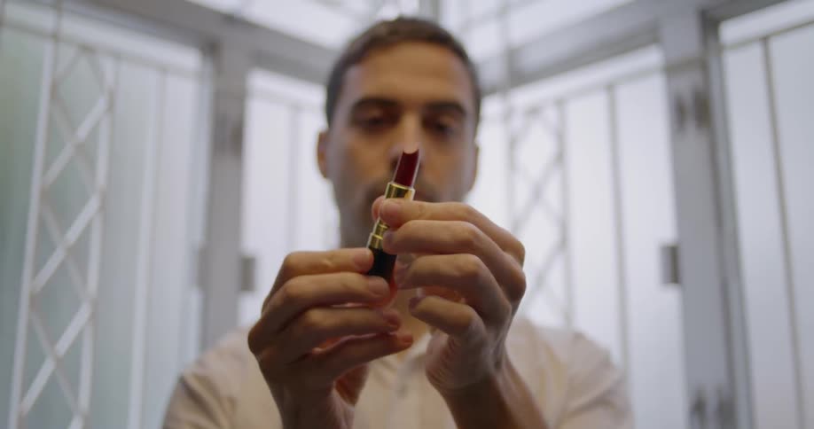A man examines a tube of lipstick