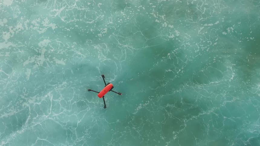The drone is flying over the rough waters