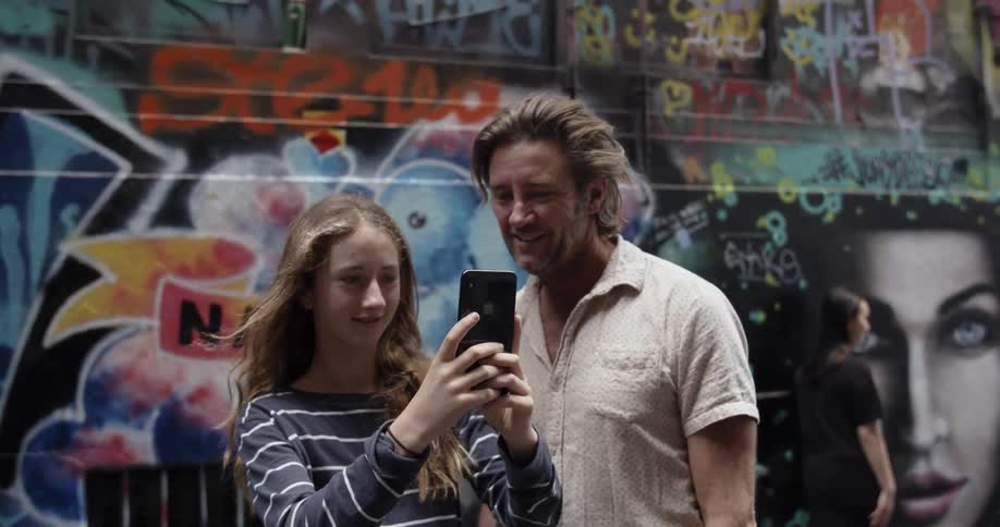 Man and teenage girl take a photograph in a city