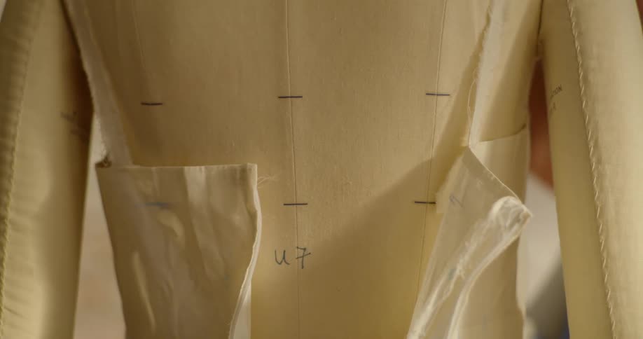 A seamstress zips up a dress on a mannequin