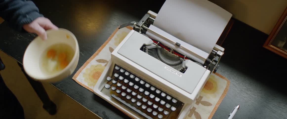 A bowl of soup sits next to a typewriter