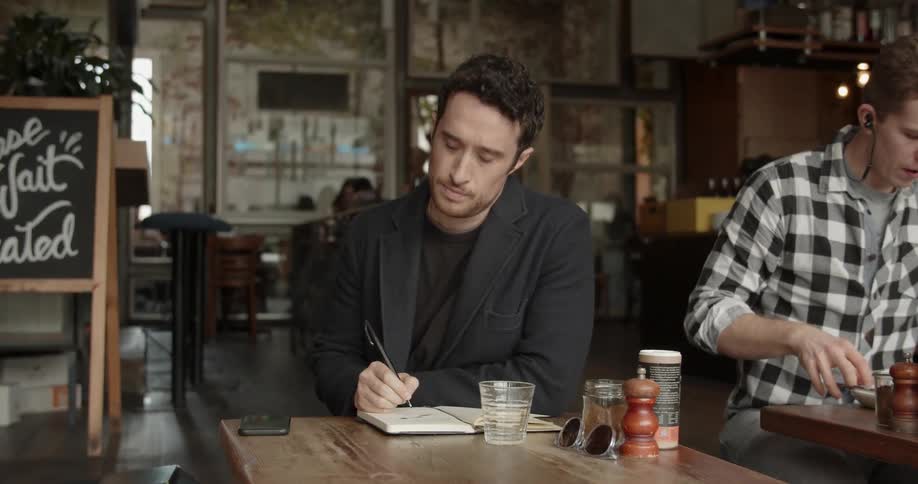 Man writes in a notebook in a coffee shop