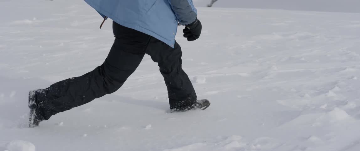 The person is wading through the tall snow