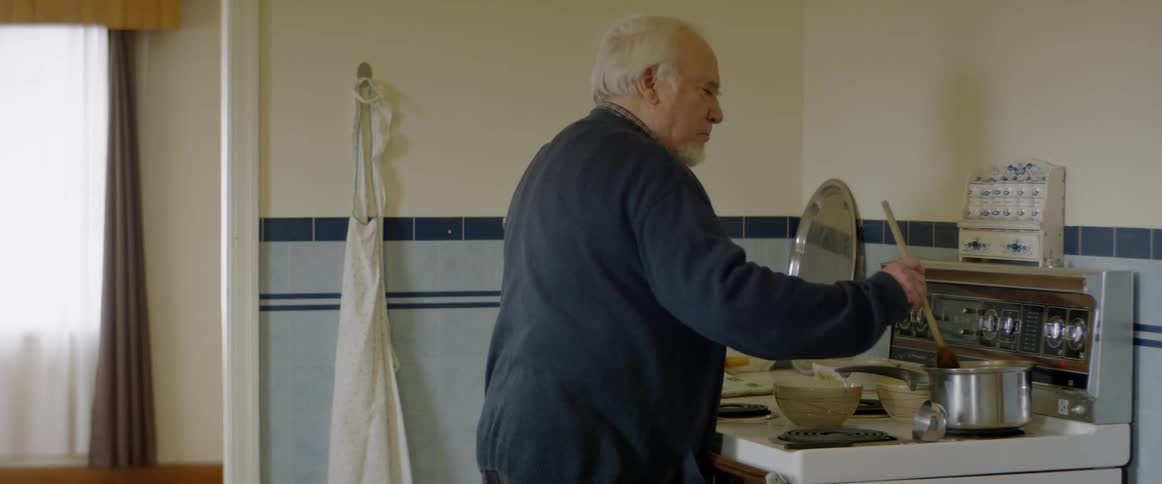 A man stirs food cooking on a stove