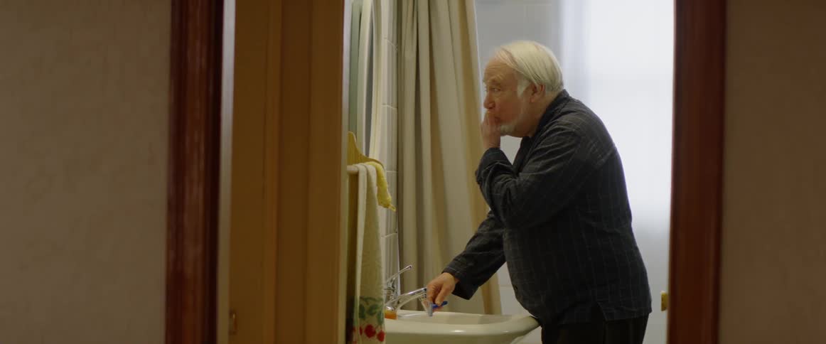 Man washes his hands in a bathroom sink and wipes his ace