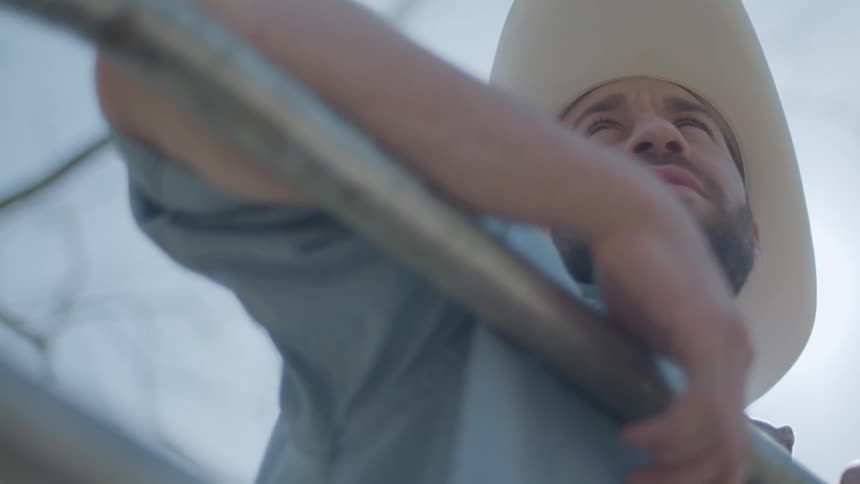 A cowboy leans over the fence