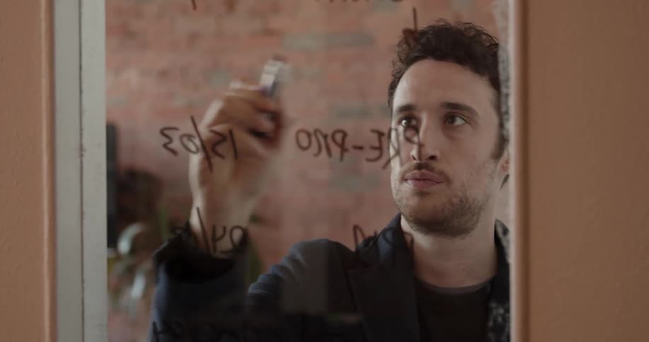 A man writes with a marker on the glass