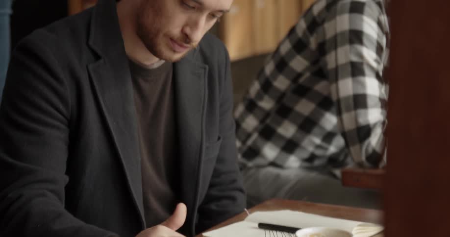 Man scrolls on his cellphone as he sits at a table